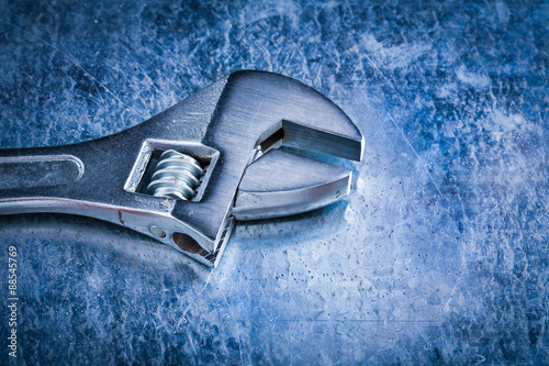 Stainless adjustable spanner on scratched metallic background to photo