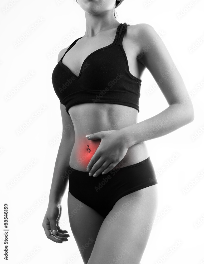 Fototapeta premium View of a toned young woman with pain standingl in studio