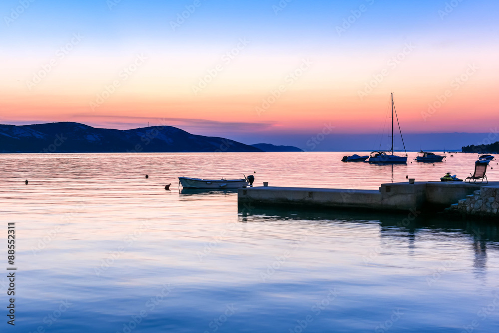 Peaceful sunset by the sea with boats and sailship