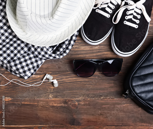 Modern girl outfit on the wooden background, top view.