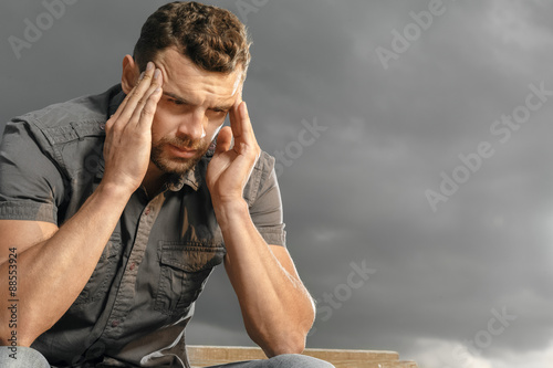 Thoughtful, depressed, handsome man in a park