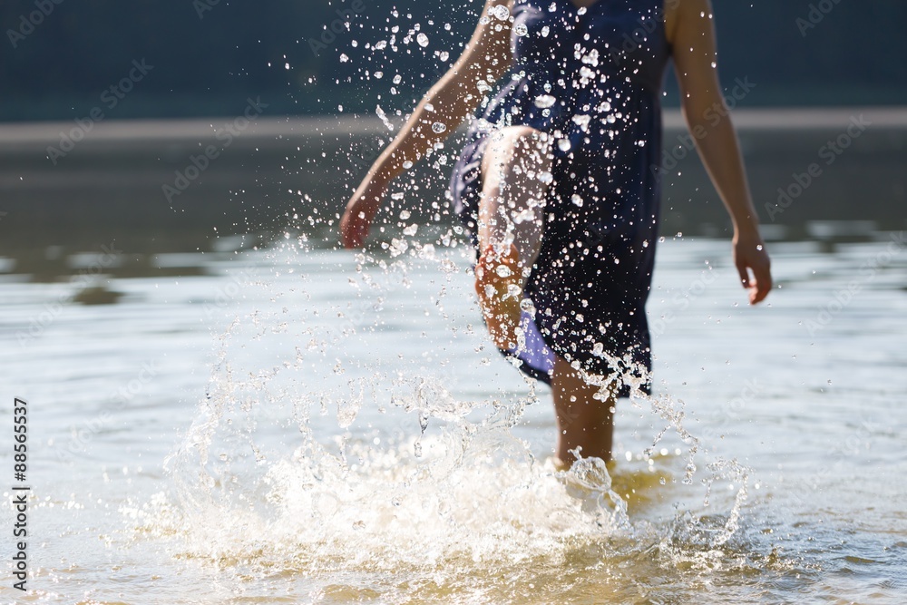 Girl splashing water in lake by her leg