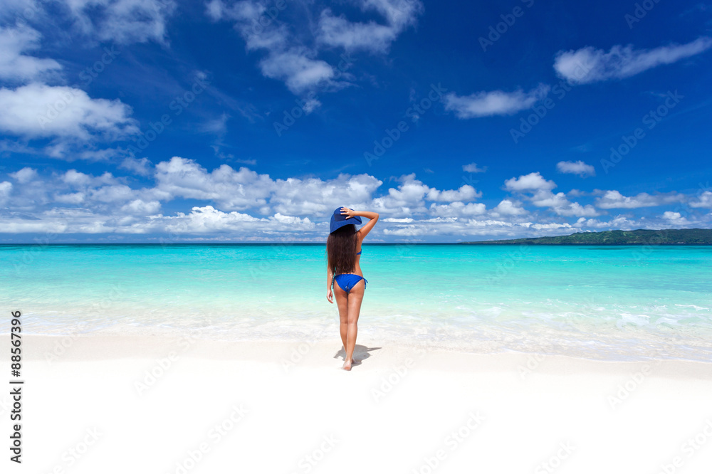 Enjoying freedom. Beautiful woman on beach in summer hat