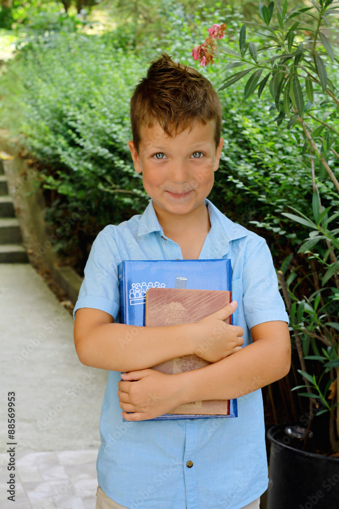 Cute boy is holding books - education concept, outdoor portrait