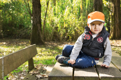 bambino seduto su un tavolo in legno in un parco