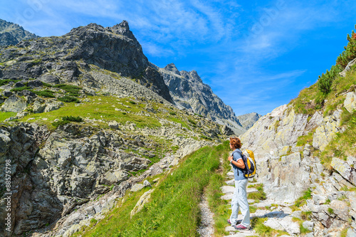 Young woman backpacker standing on hiking trail in summer landscape of High Tatra Mountains, Slovakia