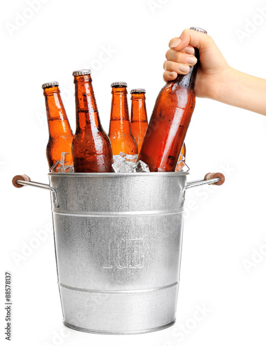 Female hand taking glass bottle of beer from metal bucket isolated on white