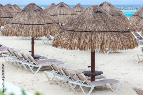 Fototapeta Naklejka Na Ścianę i Meble -  Sun umbrella and beds on caribbean beach in cloudy weather