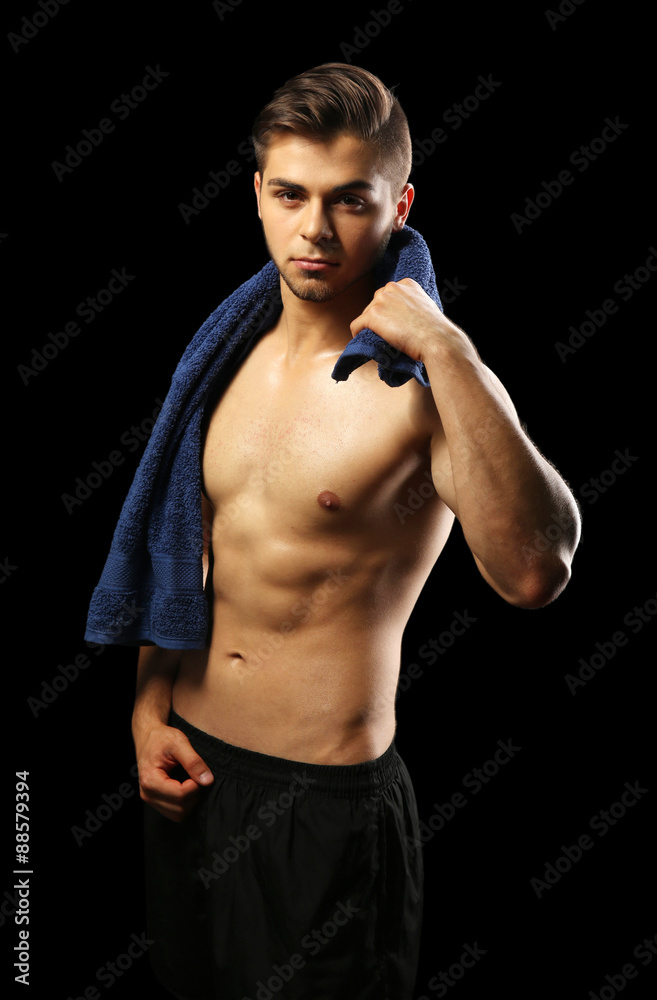 Fototapeta premium Muscle young man holding towel on dark background