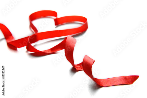 Red ribbon in shape of heart on light textured background