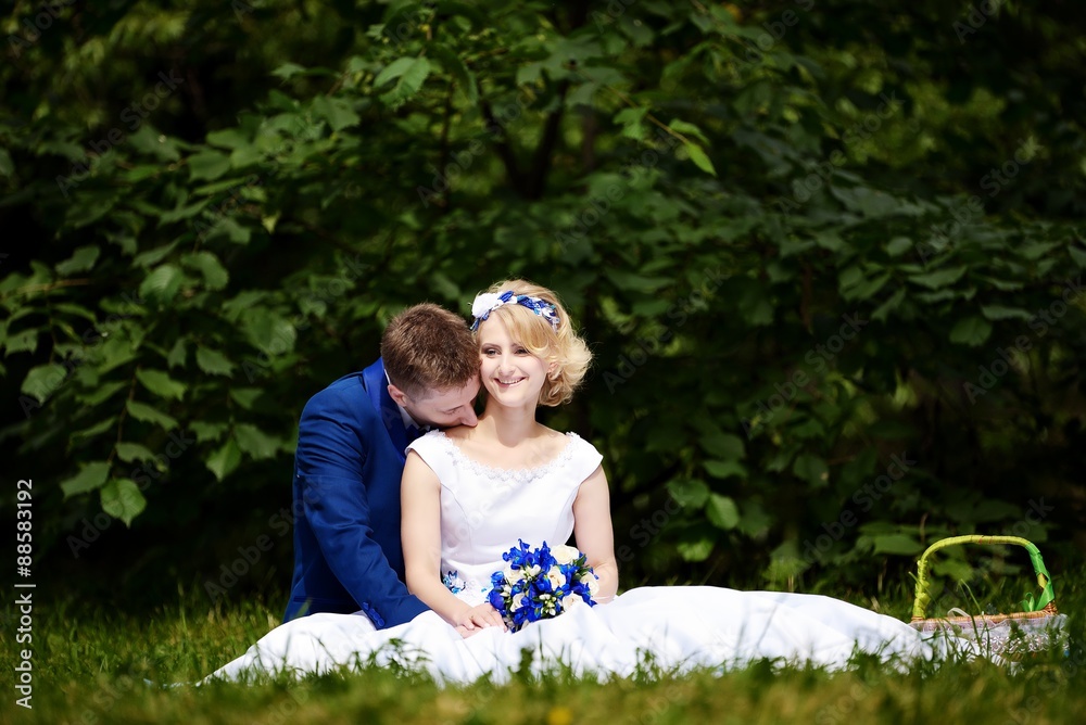 Happy bride and groom on their wedding sits on grass in park Happy bride and groom on their wedding sits on grass in park