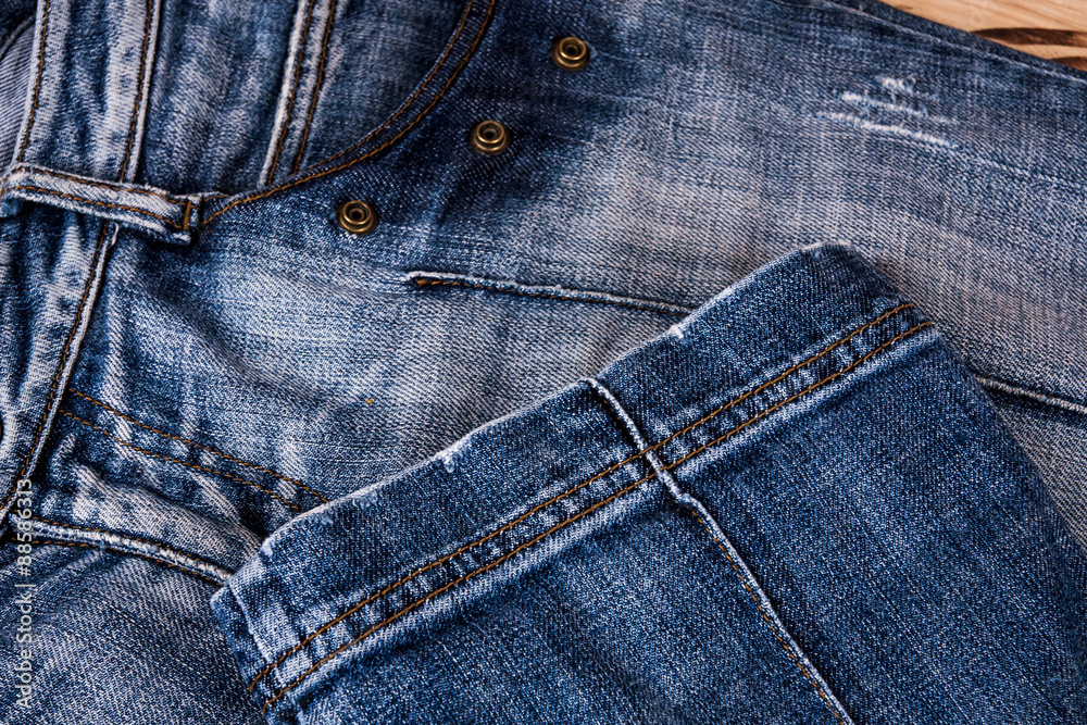 fashionable clothes. pile of jeans on a wooden background fashionable clothes. pile of jeans on a wooden background