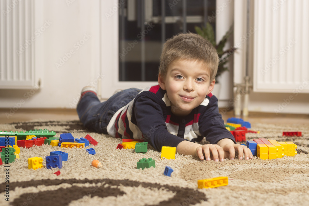 Smiling happy kid laying on carpet with toys. Smiling happy kid laying on carpet with toys.
