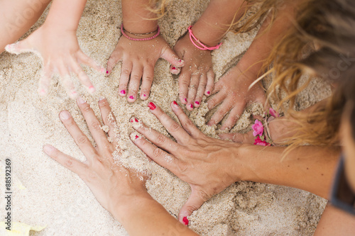 Mother and daughters hands in sand