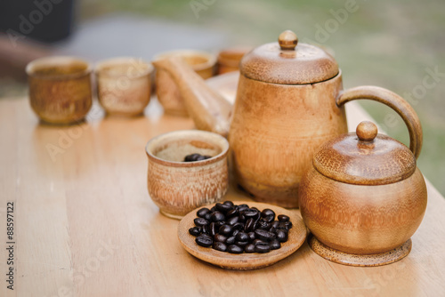 Coffee beans, cup of coffee and teapot on wooden desk. Set of ca