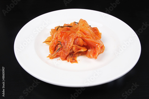 Kimchi on white plate against black background