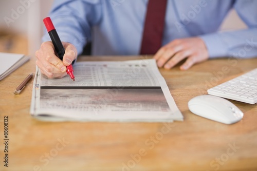 Businessman marking the newspaper with marker