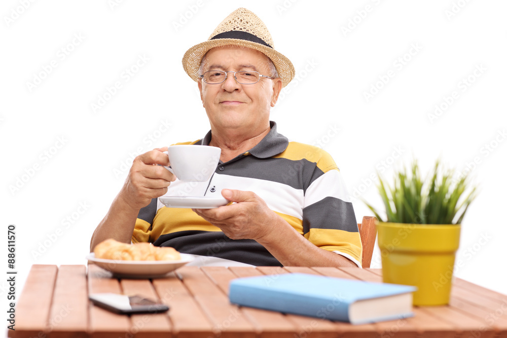 Senior gentleman drinking coffee seated at a table Senior gentleman drinking coffee seated at a table