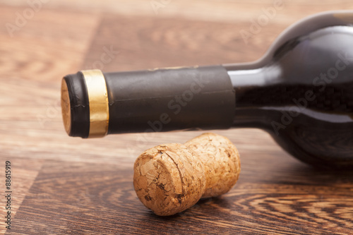 Red wine bottle and cork on wooden background