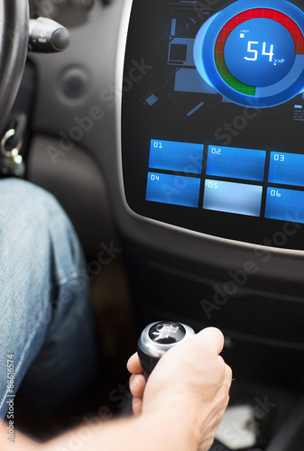 hand on car gearshift and screen with volume level