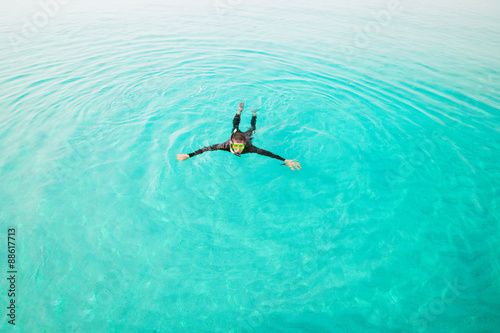 Man in diving suit swims in sea, top view. Activities on water. Diver