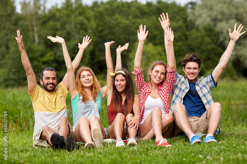 group of smiling friends waving hands outdoors