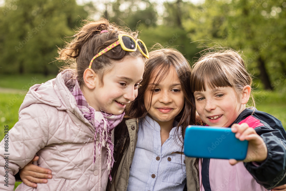 Fototapeta premium Photo of there little girls making selfie in the park