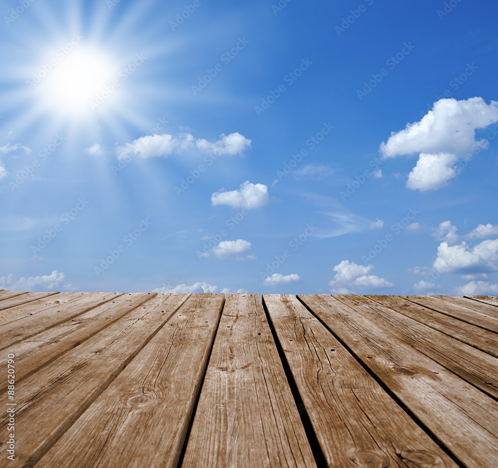 Holzsteg mit Sonne und blauem Himmel