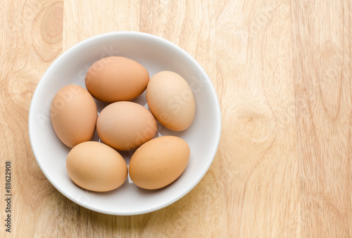 Fresh eggs in the bowl on wooden background