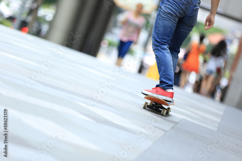 young skateboarder legs riding on skateboard on city