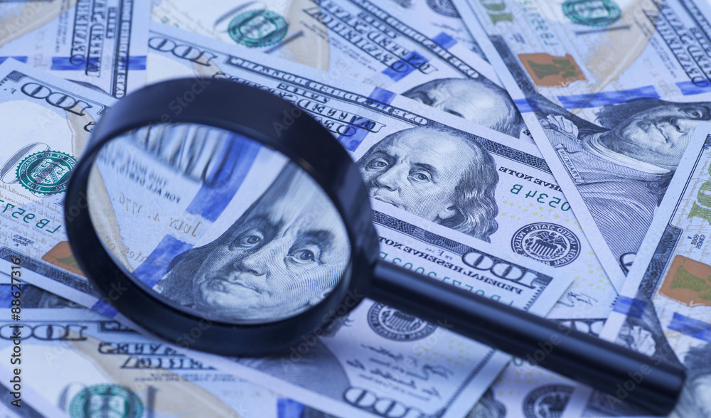 Hundred dollar banknotes under magnifying glass Hundred dollar banknotes under magnifying glass