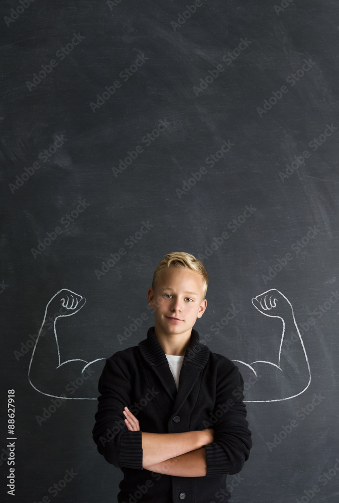 Starker Junge mit Muskeln vor Tafel