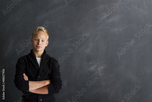 Junge mit verschränkten Armen vor Tafel