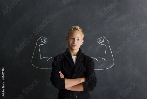 Starker Junge mit Muskeln vor Tafel photo