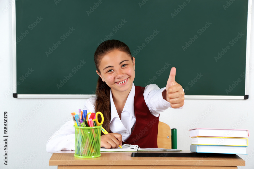 Beautiful little schoolgirl in classroom near blackboard Beautiful little schoolgirl in classroom near blackboard