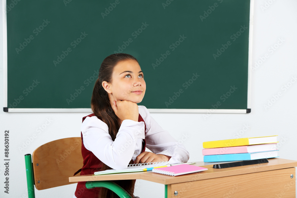 Beautiful little schoolgirl in classroom near blackboard Beautiful little schoolgirl in classroom near blackboard