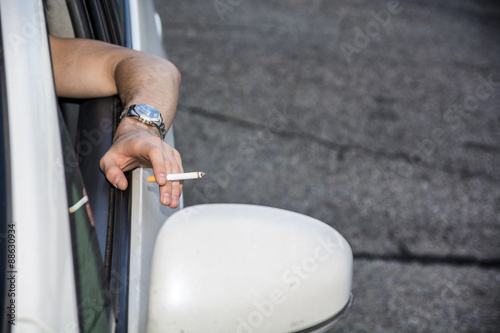 Young Man smoking cigarette while Driving