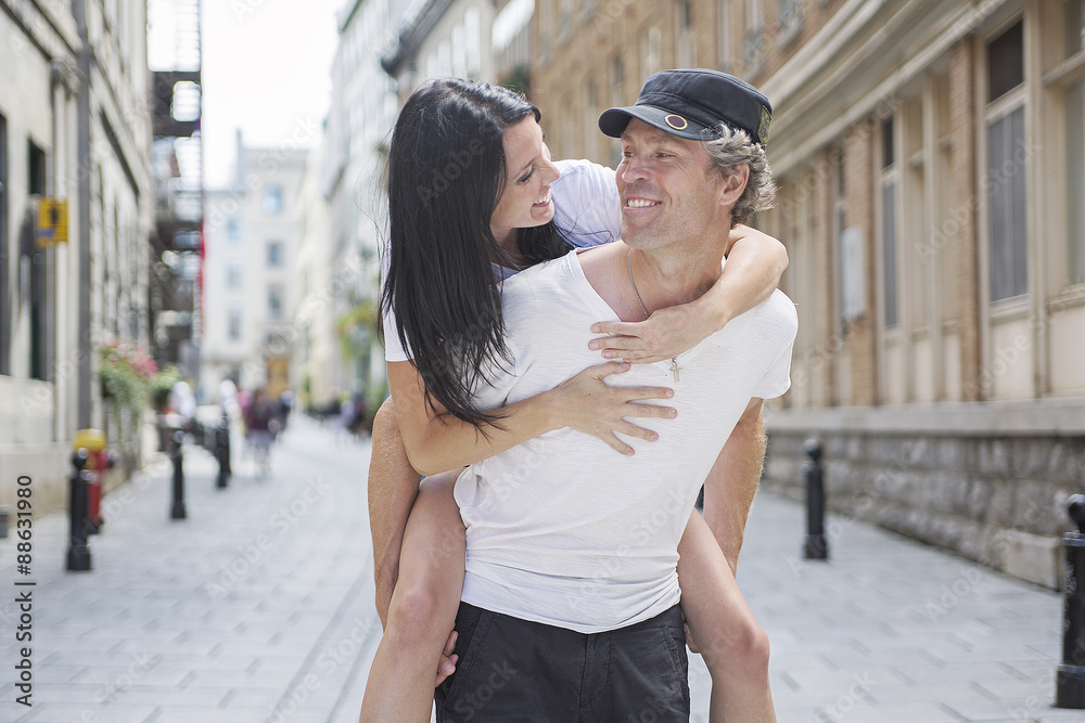 Fototapeta premium Man giving piggyback ride to girlfriend, having fun