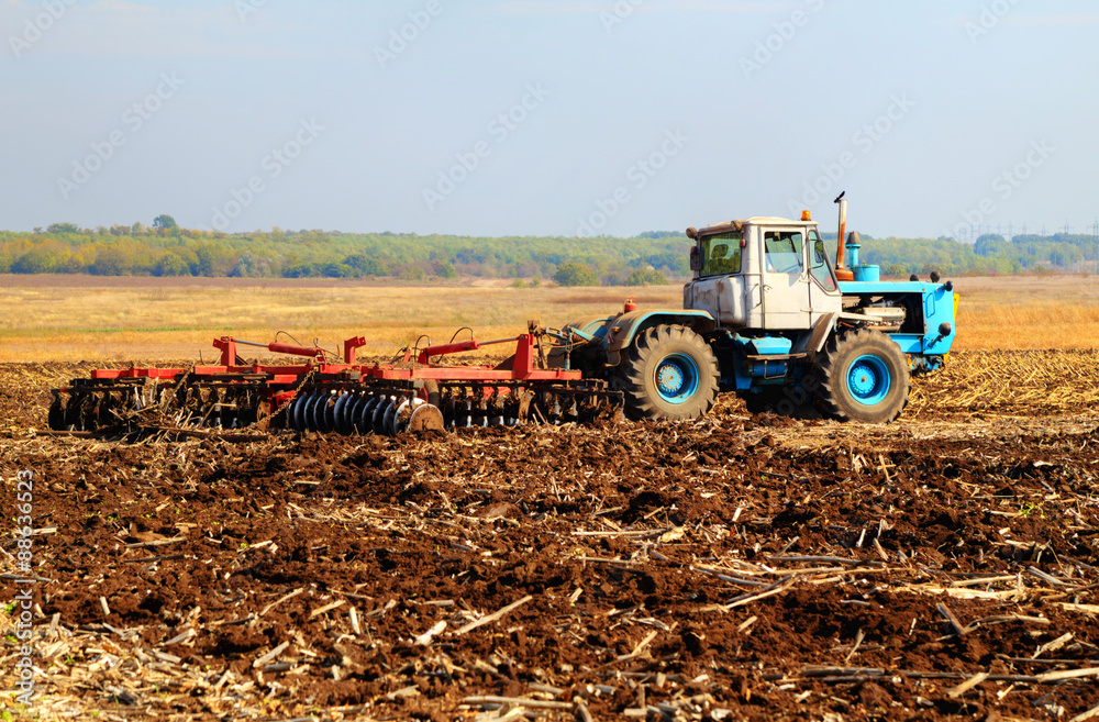 Fototapeta Farmer in tractor preparing land for sowing