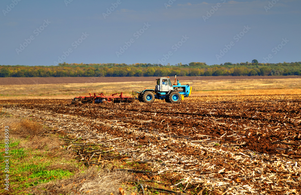 Fototapeta premium Farmer in tractor preparing land for sowing