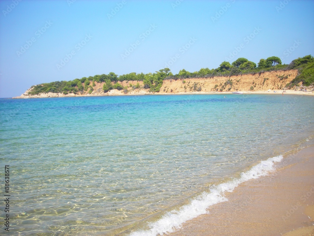 Transparent turquoise waters of the Mandraki beach on the Greek island of Skiathos, on a sunny summer day.