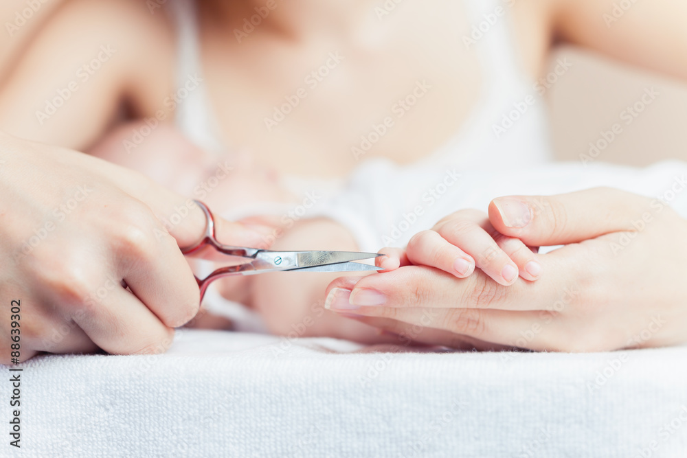 Mom tonsured nails on the hands newborn using nail scissors