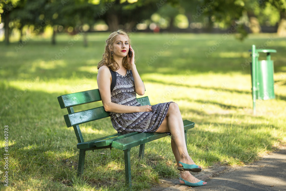 Young beautiful girl talking on the phone sitting on the bench. Young beautiful girl talking on the phone sitting on the bench.