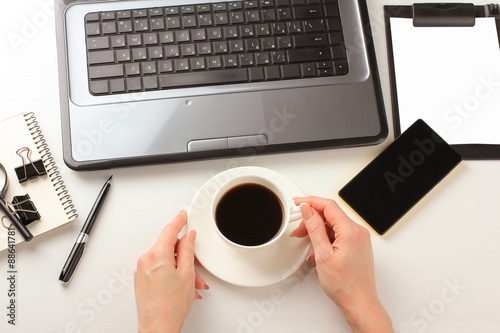 white background, laptop, a cup. notebook, pen, feminine hands, paper holder