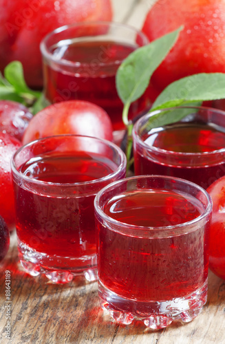 Delicious fresh juice of red and blue sweet plums in a glass on