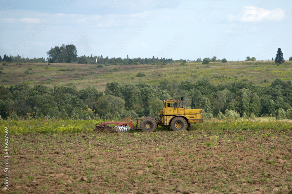 Fototapeta premium Tractor plowing the field. Rural landscape on a summer day