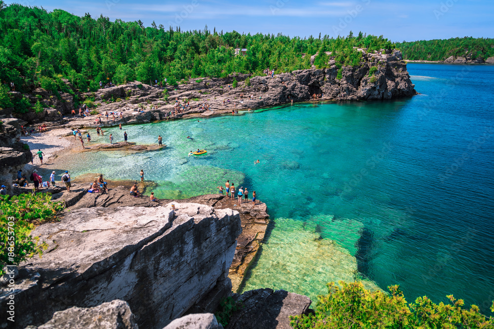 Fototapeta premium Bruce Peninsula at Cyprus lake, Ontario stunning, gorgeous amazing natural rocky beach view and tranquil azure clear water with people in background on sunny beautiful, day