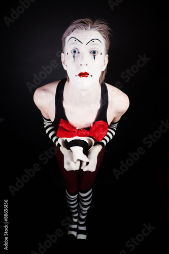 Portrait of sad mime holding hat hand