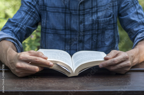 youngman reading a book on a wooden garden table