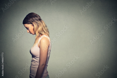 Fotografie Sad lonely woman looking down isolated on gray wall background